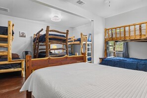 A bunk bed room with a wooden bunk bed, a single bed, and a window.