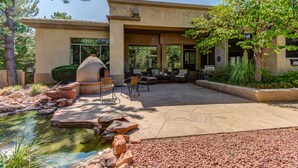 A patio area with outdoor seating, a stone water feature, and a large building with windows.