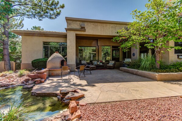 A patio area with outdoor seating, a stone water feature, and a large building with windows.