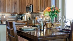 A wooden dining table with a vase of flowers, wine glasses, and plates.