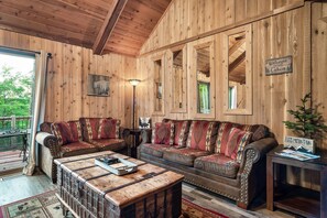 Ein Holzblockhaus-Innenraum mit einer großen Couch, einem Couchtisch und einem Schild mit der Aufschrift 'Welcome to Cabin'.