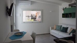 A modern living room with a dining area, white walls, a large window, and a green shelf. - La Quintecita villa with private pool -near Catania and Etna (San Giovanni La Punta)