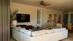 Un salón amplio con un sofá grande, un televisor de pantalla plana y un ventilador de techo.