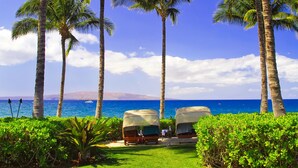 Un resort con dos sillas de descanso cubiertas y vista al océano.