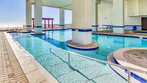 A large indoor swimming pool with clear blue water, supported by columns, and a view of the beach in the background. - Don’t Worry, Beach Happy! 3rd Floor Beachfront Condo @ Majestic ~ Sleeps 8 (Panama City Beach)