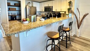 A modern kitchen with white cabinets, a granite countertop, and stainless steel appliances. - Don’t Worry, Beach Happy! 3rd Floor Beachfront Condo @ Majestic ~ Sleeps 8 (Panama City Beach)