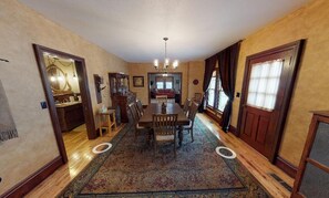 Une salle à manger avec une table et des chaises en bois, un lustre et un grand tapis.