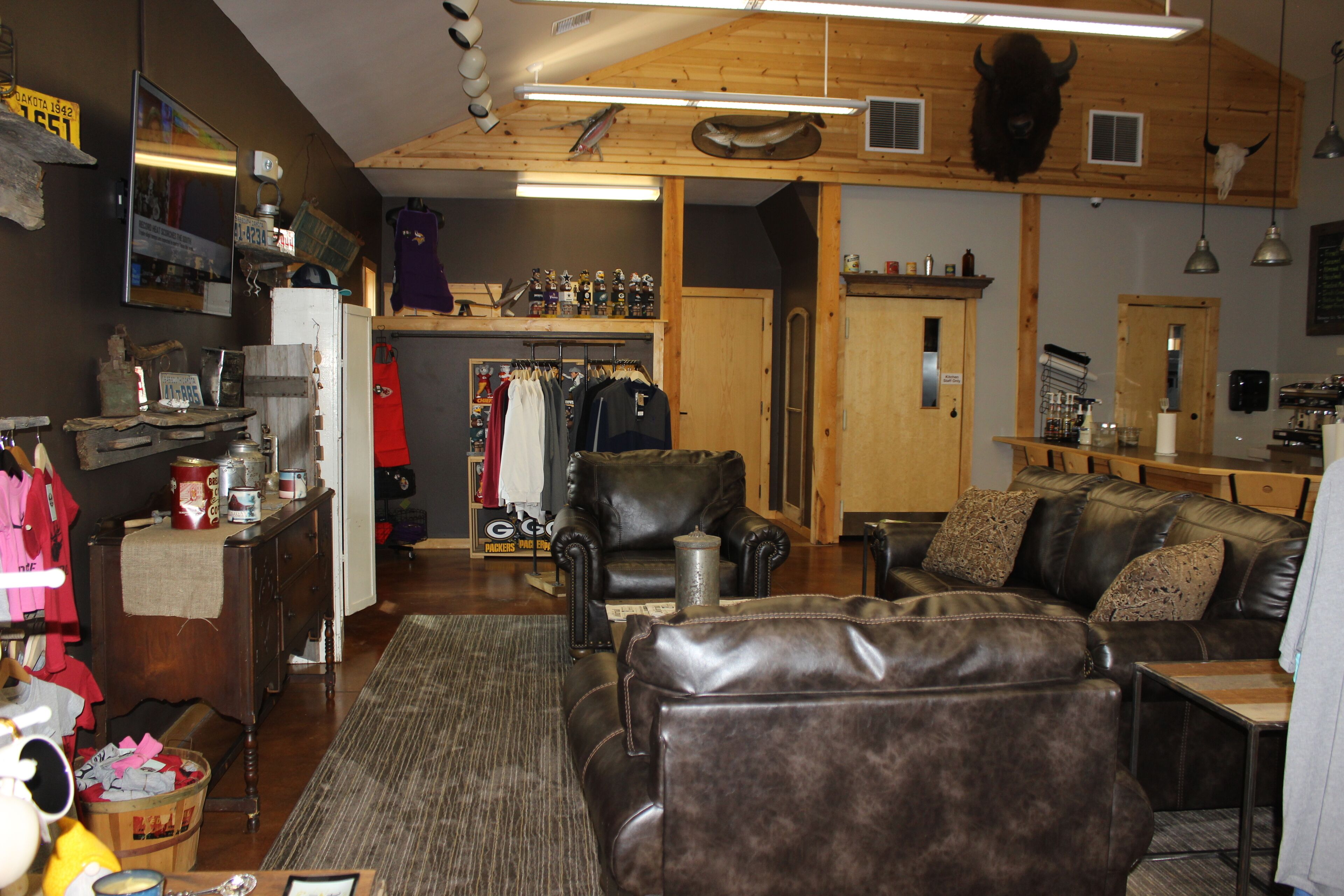 A rustic interior with a leather sofa, a dining area, and a clothing rack.