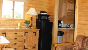 A wooden cabin interior with a kitchen, dining area, and a sofa. - Elkhorn Ridge Resort (Spearfish)