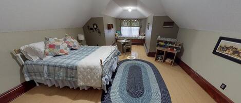 A bedroom with a bed, a desk, a chair, a rug, and a shelf with books.