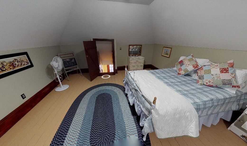 Un dormitorio con cama, cómoda, espejo, ventilador y alfombra.