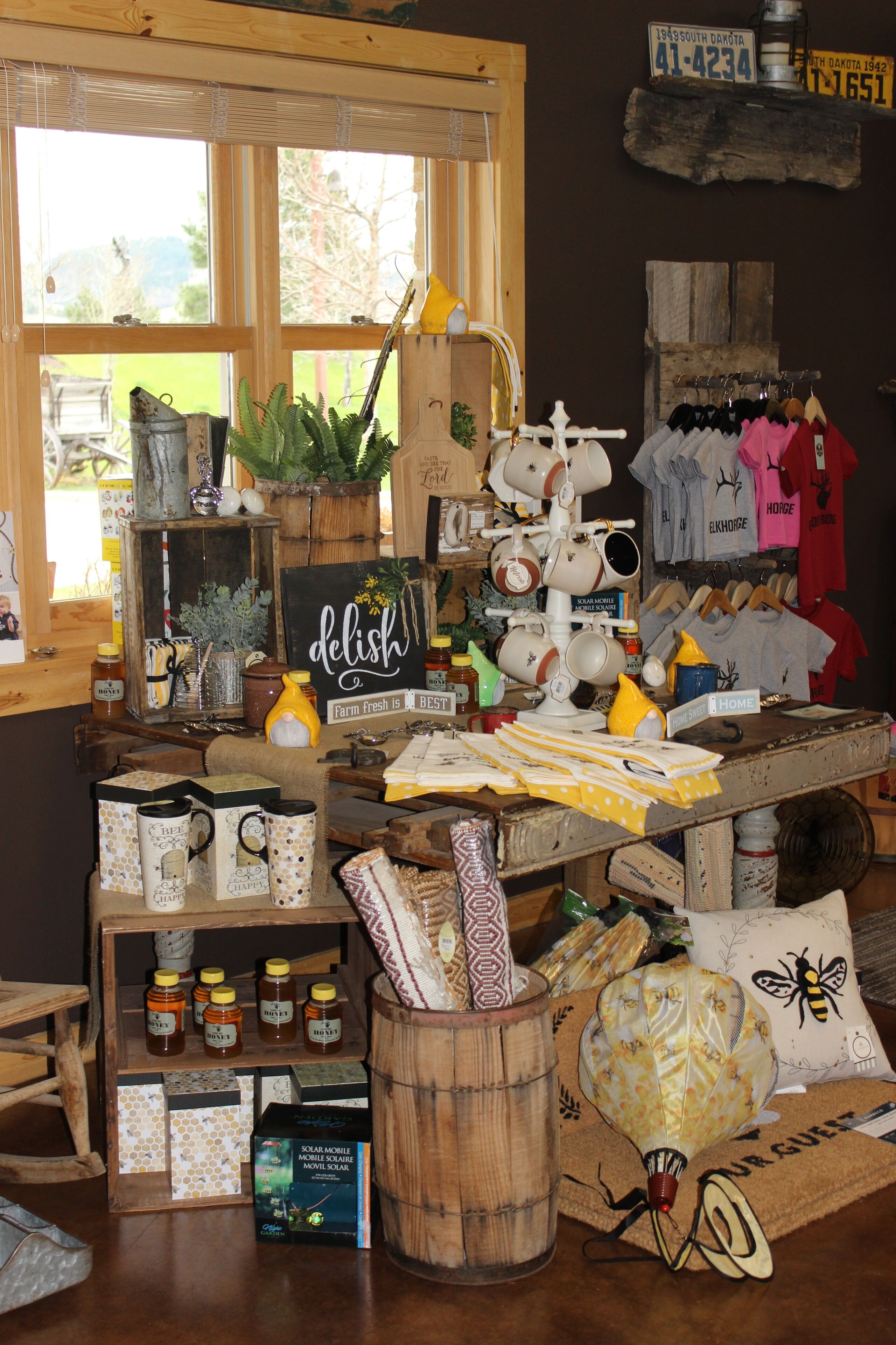 A rustic interior with wooden furniture, a variety of jars, and a display of t-shirts.