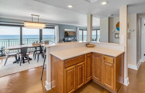 A modern kitchen with a view of the ocean, wooden cabinets, and a dining area with a view.