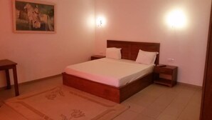 Une chambre à coucher avec un lit en bois, deux tables de chevet, une commode, un tableau au mur et un tapis à motifs floraux.