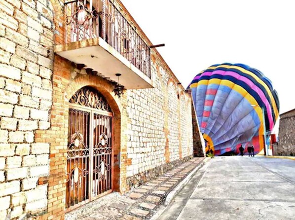 Un bâtiment historique devant lequel est garée une grande montgolfière aux couleurs vives.