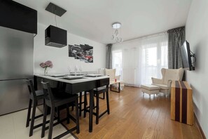 A modern kitchen with a dining area, a sofa, and a TV. - Modern Apartment | Balcony | Parking | Downtown (Wrocław)
