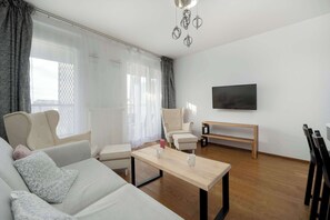 A modern living room with a sofa, armchairs, a coffee table, and a TV. - Modern Apartment | Balcony | Parking | Downtown (Wrocław)