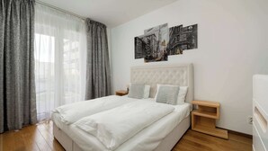 Un dormitorio con una cama grande, dos mesitas de noche, un cabecero y una obra de arte con un paisaje urbano en la pared.