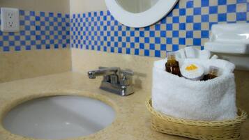 Een badkamer met een wastafel, een spiegel, een geruit behang en een mandje met toiletartikelen.