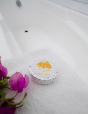 Uma banheira branca com uma toalha branca e um dosador de sabonete com design de veleiro.