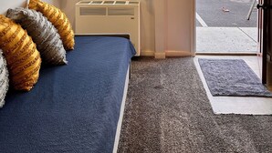 A room with a bed, a window with curtains, a radiator, a ceiling fan, and a view of a forested area outside. - Condo C at The St. Bernard (Sandpoint)