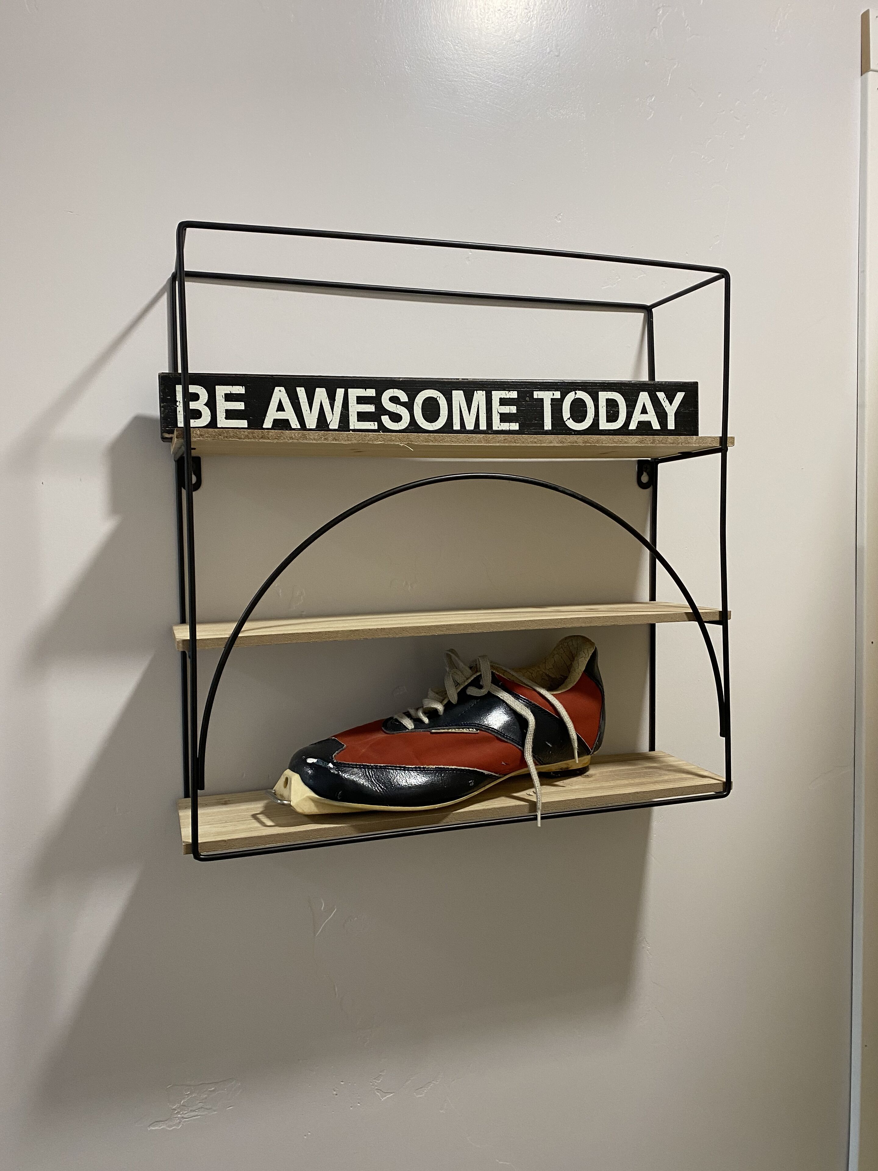 Une étagère murale agrémentée d’une affiche motivante et d’une paire de baskets.