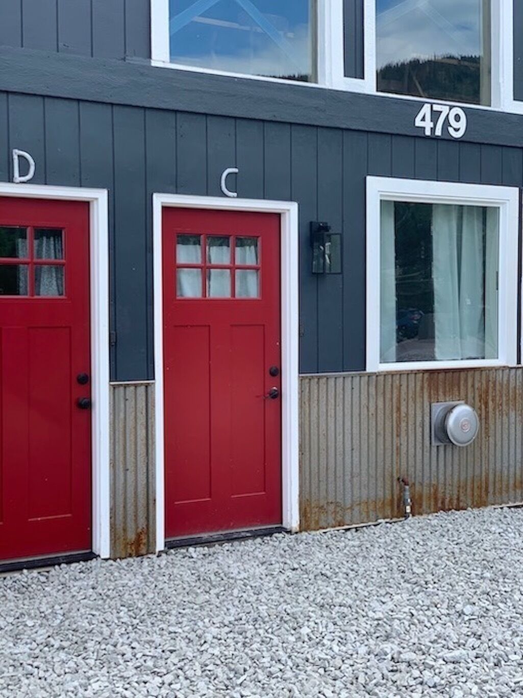 Un bâtiment avec deux portes rouges, l’une portant l’inscription « D » et l’autre « C », une fenêtre et le numéro « 479 » sur le mur.