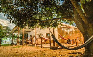 A rustic outdoor seating area with a hammock, wooden furniture, and a covered patio. - Reserva Natural El Encanto de Guanapalo (San Luis de Palenque)