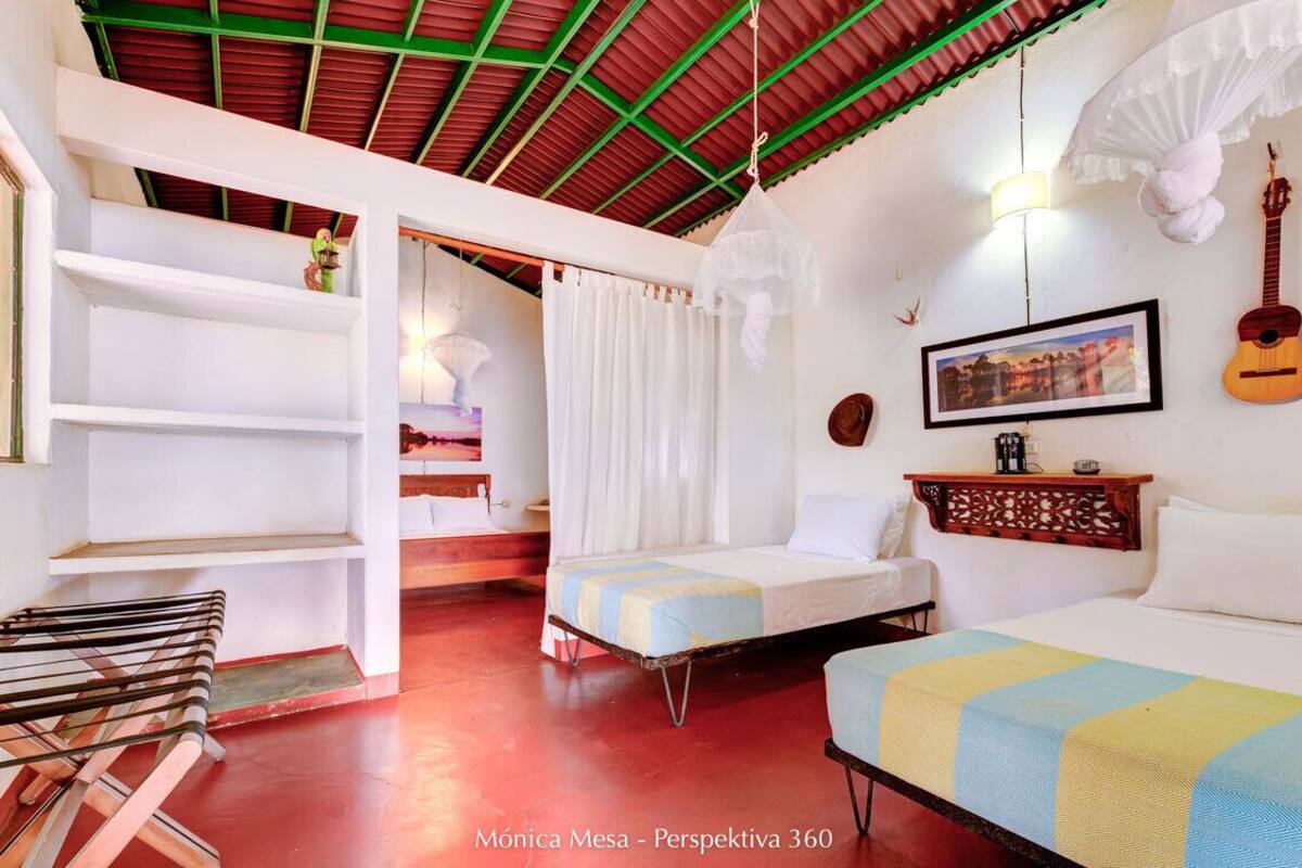 Una habitación acogedora con dos camas, un sillón colgante y una guitarra en la pared.