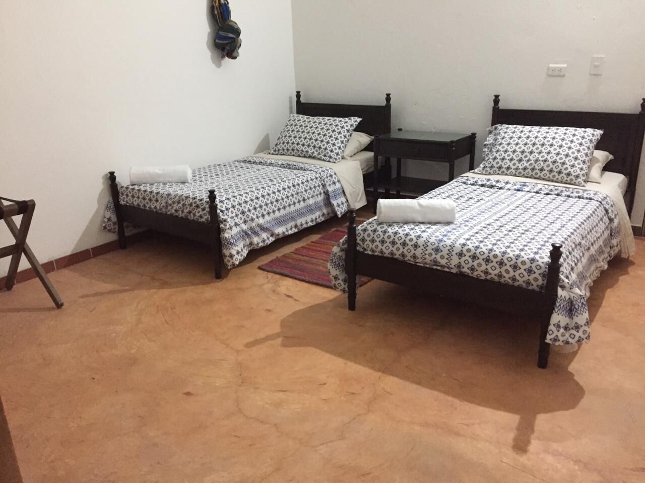 Una stanza con due letti singoli, un tavolino e una sedia.