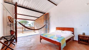 A bedroom with a wooden bed, a hammock, and a view of the outdoors. - Reserva Natural El Encanto de Guanapalo (San Luis de Palenque)