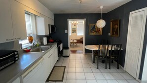 A modern kitchen with white cabinets, a black countertop, and a dining area with a table and chairs. - Minutes to Midtown NYC, sunny, super clean modern 2 bedroom beautiful apartment (West New York)