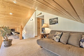 A cozy living room with a wooden ceiling, a sofa, a lamp, and a potted plant.
