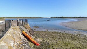 Vista costera con un espigón, un kayak y un bote en el agua.