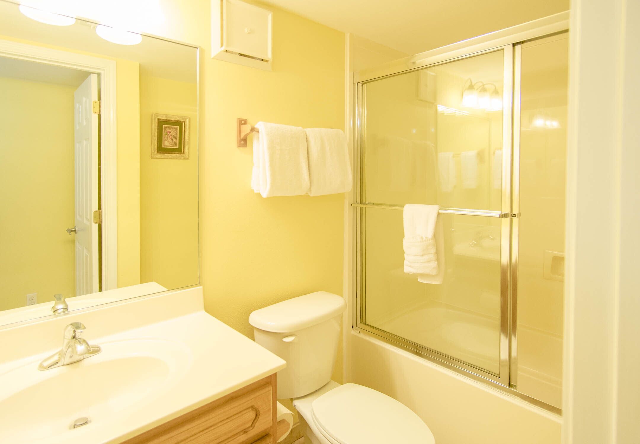 A bathroom with a sink, toilet, and glass shower enclosure.