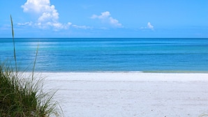 A beach with clear blue water and a white sandy shore.