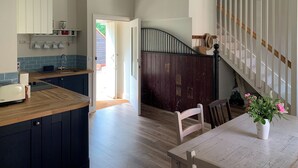 A modern kitchen with dark cabinetry, a wooden countertop, and a dining area with a table and chairs. - The Stable was renovated in 2020 to enhance your stay in the Canterbury area. (Womenswold, near Canterbury)