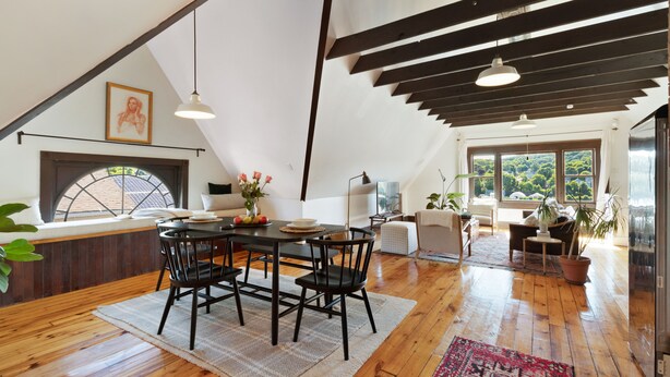 A spacious loft with a dining area featuring a wooden table and chairs, a large window with a view of greenery, and a high ceiling with exposed beams. - The Pearl, NH hidden luxury close to the Quinnipiac River in historic property (New Haven)