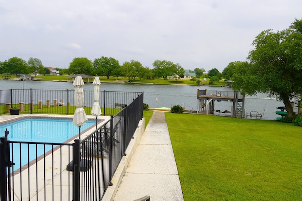View of pool, yard, dock, and lake from back porch.