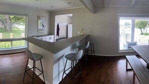 Une cuisine moderne avec un coin bar, de grandes fenêtres et une vue sur l’extérieur.