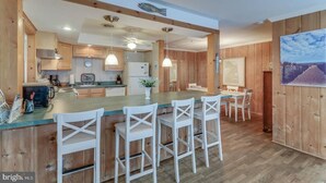 Una cocina moderna con armarios de madera, una isla central con taburetes y luminarias colgantes, y un ventanal con vistas.