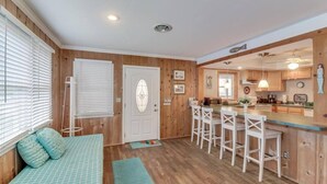 Una habitación acogedora con una cama, un pequeño rincón de descanso y una cocina con taburetes de bar.
