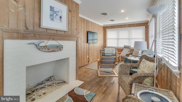 Una sala de estar acogedora con chimenea, paredes de madera y un área de descanso cómoda con un sofá y sillones.