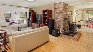 Een woonkamer met een open haard, een bank, een televisie en een boekenkast.