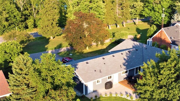 A residential area with a house featuring a sloped roof, a front yard with two lawn chairs, and a large tree in the center. - Alba Cottage with Brand New Pool  (Niagara-on-the-Lake)