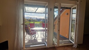Eine offene Schiebetür führt zu einer Terrasse mit Tisch und Stühlen.