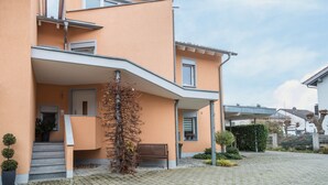 A multi-story building with a curved facade, a staircase leading to an entrance, and a bench outside. - Apartment 'Haus Sonnenseite Säntis' with Mountain View, Balcony and Wi-Fi (Wasserburg)