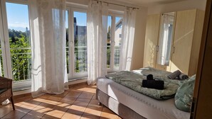 A bedroom with a large bed, a wardrobe, and a balcony with curtains. - Apartment 'Haus Sonnenseite Säntis' with Mountain View, Balcony and Wi-Fi (Wasserburg)
