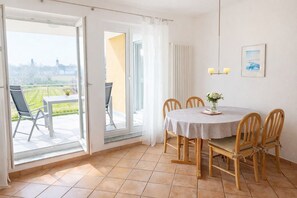 Un espace repas comprenant une table et des chaises, une vue sur l’extérieur et une fenêtre avec des rideaux.