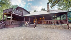 A rustic cabin with a covered porch and a separate upper deck.